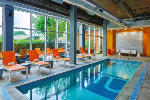 uma piscina interior com cadeiras e cadeiras laranja ao lado de um edifício em Aloft Houston by the Galleria em Houston