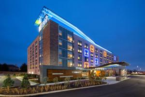 a hotel building with a lit up facade at night at Aloft Louisville East in Louisville