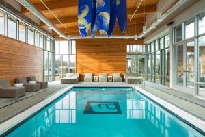 a swimming pool with chairs and a large pool at Aloft Louisville East in Louisville