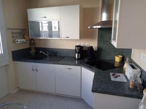 uma cozinha com armários brancos e um balcão preto em Firminy, centre-ville. em Firminy