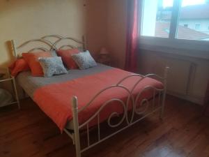 um quarto com uma cama com um cobertor laranja e uma janela em Firminy, centre-ville. em Firminy