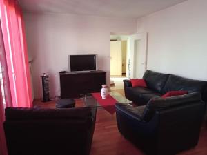 a living room with black leather furniture and a flat screen tv at Firminy, centre-ville. in Firminy