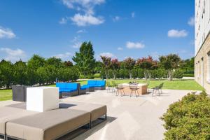 een patio met tafels en stoelen in een park bij Aloft Hotel Frisco in Frisco