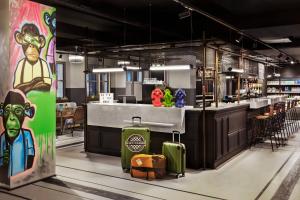 a restaurant with a bar with a counter with luggage at Moxy Lille City in Lille
