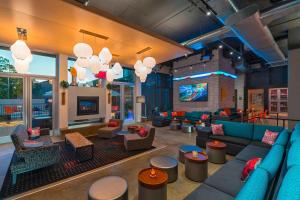 a large living room with blue couches and tables at Aloft College Station in College Station