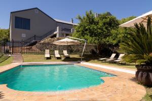 a swimming pool with chairs and an umbrella at Protea Hotel by Marriott Cape Town Tyger Valley in Bellville