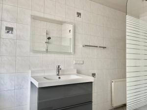 La salle de bains blanche est pourvue d'un lavabo et d'un miroir. dans l'établissement Homely Stay Apartment 1, à Sankt Pölten