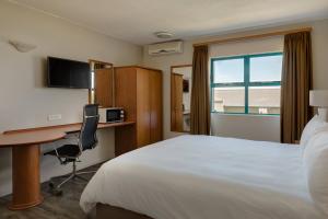 a hotel room with a bed and a desk and a window at Protea Hotel by Marriott Cape Town Tyger Valley in Bellville