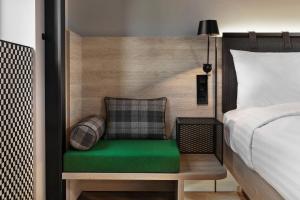 Moxy Lille City في ليل: غرفة نوم بسرير ومقاعد خضراء