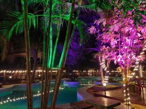 a pool at night with palm trees and lights at CHARULATA RESIDENCY in Bolpur
