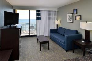 sala de estar con sofá azul y TV en Four Points by Sheraton Virginia Beach Oceanfront, en Virginia Beach