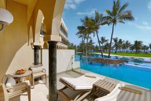 a resort balcony with chairs and a swimming pool at Al Bustan Palace, a Ritz-Carlton Hotel in Muscat