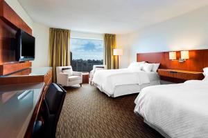 um quarto de hotel com duas camas e uma televisão de ecrã plano em The Westin Ottawa em Ottawa