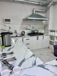 a kitchen with white cabinets and a marble counter top at Hostel_inJoy in Shymkent