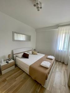 a white bedroom with a large bed and a window at NEWHOUSE ROOFTOP in Nettuno
