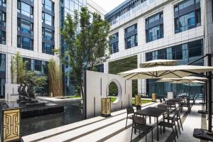 a patio with tables and umbrellas in front of a building at Fairfield by Marriott Taizhou Bay in Taizhou