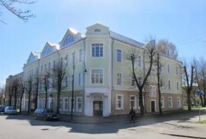 un grand bâtiment avec une personne qui marche devant lui dans l'établissement Avers House, à Narva