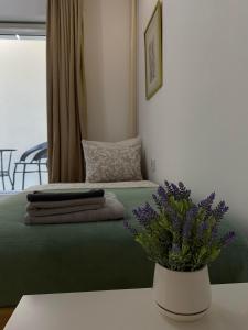 ein Schlafzimmer mit einem Bett mit einer Vase mit lila Blumen in der Unterkunft Apartmani Maximus in Subotica