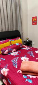 ein Bett mit einer roten Tagesdecke mit Blumen darauf in der Unterkunft Lyn Melaka Homestay in Malakka