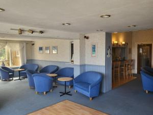 a waiting room with blue chairs and a bar at Eastmount Hall Hotel in Shanklin