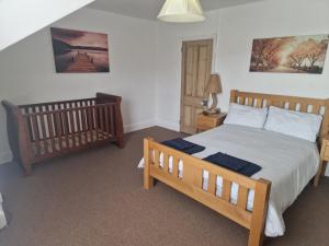 a bedroom with a wooden bed and a crib at Looe Spacious 4 Double bedroom House Sleeps 9 Harbour River Views in Looe
