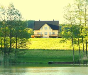 dom siedzący na szczycie wzgórza obok jeziora w obiekcie Apartamenty Nad Jeziorem w mieście Postawele