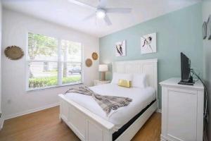 Un dormitorio con una cama blanca y un televisor. en Relaxing, Private Family Home At Lake Berkley Resort, South Facing Pool, Near Disney, SeaWorld, en Kissimmee 33 fotos más