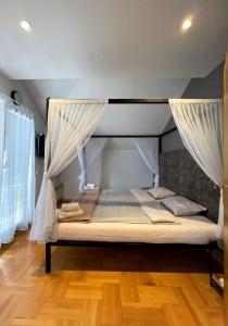 a bedroom with a canopy bed with curtains at Town hostel in Peje