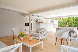 uma sala de estar com cadeiras brancas e uma mesa em Grande villa, vue 360° sur lagon em Le François
