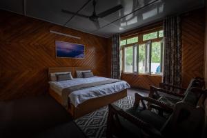 a bedroom with a bed and a chair and a window at Sultan's Guest House in Skardu