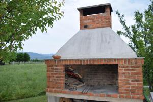 a brick oven with a roof on a field at Apartman Maga in Čapljina