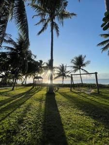 a park with palm trees and a swing set at Bitingui Praia Hotel in Japaratinga