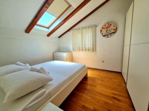 um quarto com uma cama branca e uma clarabóia em Apartments Roko em Zadar