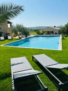 una piscina con 2 sillas y una mesa al lado en L'arbre qui chante, en Saint-Étienne-de-Sermantin