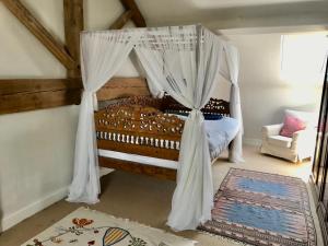 a bedroom with a canopy bed and a chair at Mulberry Barn in Micheldever