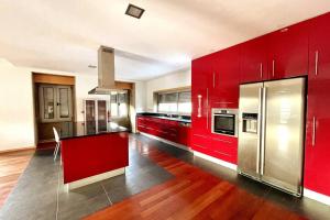 uma cozinha com armários vermelhos e um frigorífico de aço inoxidável em Casa Castelhano - Minho Braga em Mire de Tibães