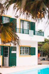 una casa con persiane verdi e una piscina di The Kitesurf Lodge a Casal do Narcizo