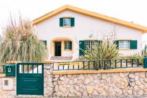 una casa bianca con porte verdi e un muro di pietra di The Kitesurf Lodge a Casal do Narcizo