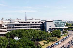 duży budynek z samochodami zaparkowanymi przed nim w obiekcie AC Hotel Paris Porte Maillot by Marriott w Paryżu