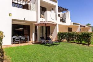 uma casa com cadeiras e um guarda-sol no quintal em RochAlvor em Alvor