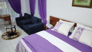 a bedroom with a bed and a chair at Charlestina Beach Resort in Ampeni