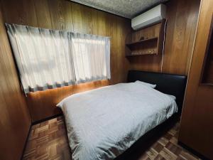 een kleine slaapkamer met een bed en een raam bij SUMITSUGU HOUSE Grandpa in Kumamoto