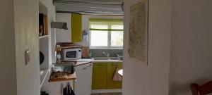 a kitchen with yellow and green cabinets and a microwave at gite Sous le Figuier in Vals-les-Bains