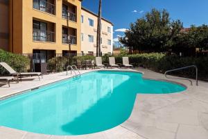 a swimming pool with chairs and a building at Courtyard by Marriott Tucson Williams Centre in Tucson