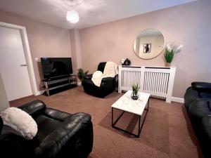 レスターにあるComfy Casa - Syster Properties Serviced Accommodation Leicester Families, Work, Groups - Sleeps 13のリビングルーム(黒革の家具、鏡付)