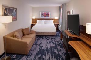 a hotel room with a bed and a couch and a television at Fairfield Inn & Suites New York Manhattan/Downtown East in New York