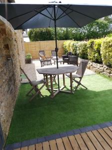 een tafel en stoelen met een parasol op het gras bij Charmante longère en pierres refaite à neuf in Moëlan-sur-Mer