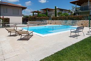 un patio avec deux chaises et une piscine dans l'établissement APARTMENT YIN & YANG - Regarda Travel, à Lazise