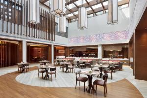 a rendering of a restaurant with tables and chairs at Courtyard by Marriott Raipur in Raipur