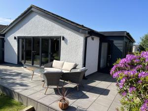a patio with a couch and chairs and some flowers at Stylish Modern Home with Parking Enclosed Garden in Holyhead